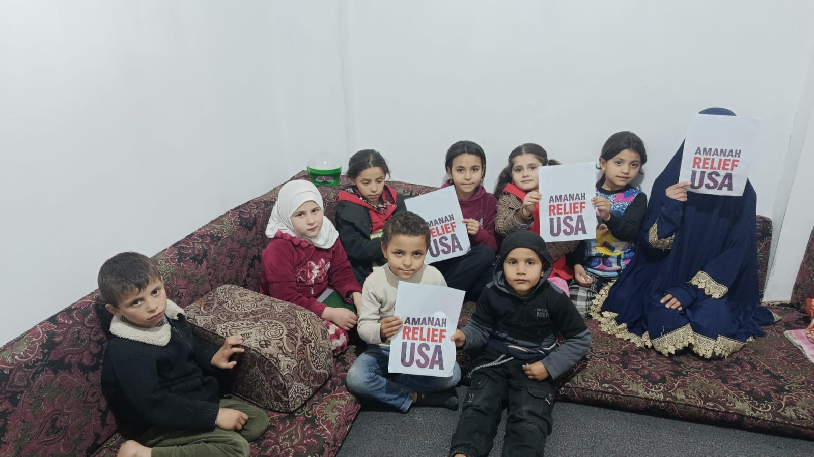 Children in Syria holding Amanah Relief USA signs