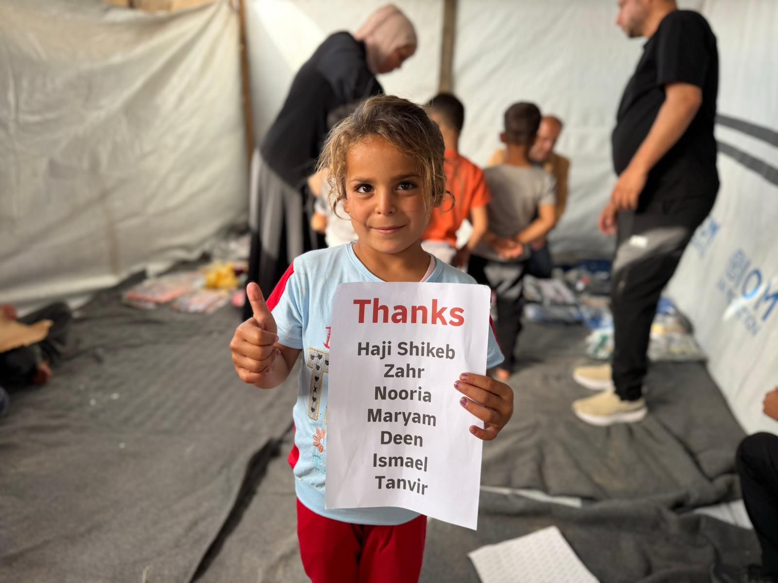 A girl holding a thank-you sign to donors